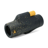 Black and gold monocular with textured grip on a white background