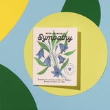 Sympathy card with blue flowers on a circular yellow and green background, printed on paper. Suitable for expressing condolences.