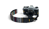 Pentax camera with a colorful strap on a white background