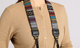Person wearing a beige shirt with a colorful patterned strap over the shoulder on a plain background
