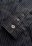 Dark wash shirt sleeve with orange stitching and metal snaps, showing durable denim material for casual wear.