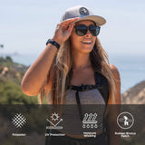 Woman wearing a grey snapback hat outdoors; icons show its breathable and moisture-wicking, ideal for active use.