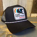 Black mesh 5-panel trucker hat with rope accent and surfer patch, suitable for casual or beach wear.