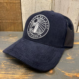 Navy corduroy 6-panel trucker hat with California patch, displayed on a wooden surface.