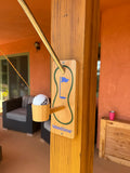 A green fabric golf swing putt practice set hangs from a porch post; outdoor patio furniture sits in the background.