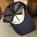 Navy and red trucker hat with mesh back, turned upside down on a wooden surface.