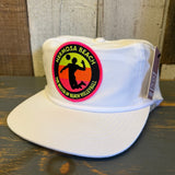 White nylon/cotton beach volleyball hat with patch, resting on a wooden surface.