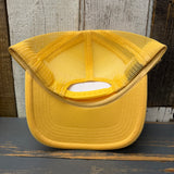 Sunset yellow foam trucker cap, turned inside out, displayed on a rustic wooden surface.