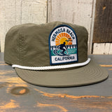 Army green and white surf rope cap with patch reading 1 to 3 Feet High & Rising; casual fabric, outdoor use.