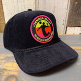 Black corduroy cap with a beach volleyball patch, displayed on a rustic wooden surface.