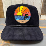 Black corduroy cap featuring a sunset patch, pier, lifeguard tower, and Hb details. Ideal for casual outdoor wear.