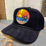 Black corduroy cap with a sunset patch showing a pier, ocean, and Hb lettering; casual, everyday wear.