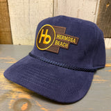 Navy blue corduroy baseball cap on wooden surface, featuring classic panel design and curved brim.