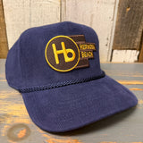 Navy blue corduroy cap with a yellow patch, displayed on a wooden surface.