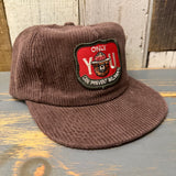 Java brown corduroy hat with Smokey Bear patch, displayed on a wood surface.