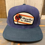 Navy and dark green 6-panel cap with low profile, featuring a palm tree and sunset patch; suitable for casual wear.