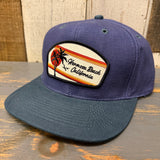 Navy and dark green 6-panel low profile cap with patch featuring palm tree and sunset design. Cotton blend, casual wear.