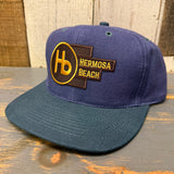 Navy and dark green 6-panel low profile baseball cap featuring HB initials and logo on the front.