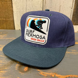 Six-panel cap in navy and dark green with an embroidered patch, suitable for daily wear.