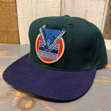 Dark green and navy volleyball patch cap on wood surface; cloth material, casual use.