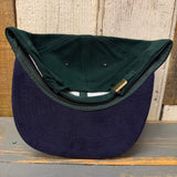Dark green/navy low profile cap shown inside out; brass clasp detail visible on fabric closure.