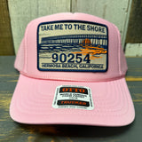 Pink mesh trucker hat featuring a sunset pier graphic, ideal for casual beachwear and sun protection.