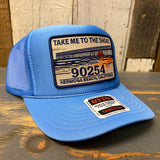 High crown blue trucker hat with a patch on a wooden surface