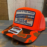 Neon orange and brown trucker hat with a patch on a wooden surface.