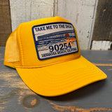 Gold trucker cap with a patch on a wooden surface