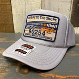 Grey trucker hat with a curved brim and patch, mesh back panels, designed for casual outdoor wear.
