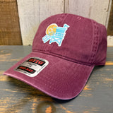 Maroon dad hat with a colorful lifeguard tower patch, made of cotton, sits on wooden surface.