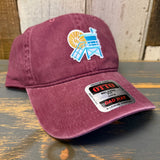 Maroon cotton dad hat with LIFEGUARD TOWER design sits on a wooden surface, suitable for casual wear.