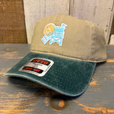 Dark green and khaki 6-panel dad hat with lifeguard tower design, low profile, displayed on a wooden surface.