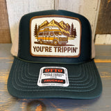 Green trucker hat with a khaki mesh back and a 'You're Trippin' design and Otto label on a wooden surface
