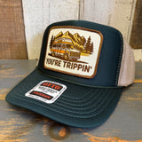 Green and khaki trucker hat with 'You're Trippin'' design and Otto logo on a wooden surface