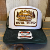 White trucker hat with green bill and a 'You're Trippin' design and Otto brand label on a wooden surface.