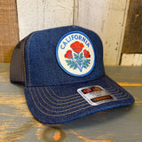 Blue denim trucker hat with California poppy patch on a wooden surface