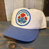 White and blue cap with California poppy design on a wooden surface