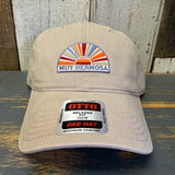 Khaki cap with 'Muy Hermosa' logo and 'OTTO' label on a wooden surface