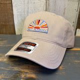 Khaki cap with a colorful patch and brand label on a wooden surface