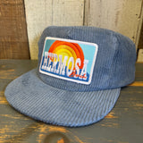 Slate blue cap with a colorful "Hermosa Beach" patch on a wooden surface