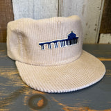 Beige corduroy cap with a logo on a wooden surface