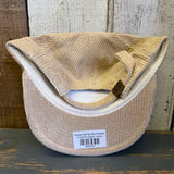 Upside-down beige corduroy cap with a brand tag on a wooden surface