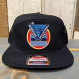 Black cap with a colorful "Hermosa Volleyball" logo on a wooden surface