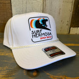 White cap with 'Surf Hermosa' logo on a wooden surface