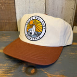 White cap with brown bill featuring a 'South Bay Surf California' logo on a wooden surface.