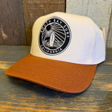 white canvas trucker hat with a black and white 'South Bay Surf California' patch and a mustard brown brim on a wooden surface