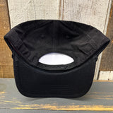 Black corduroy cap, underside view, displayed on rustic wood surface.