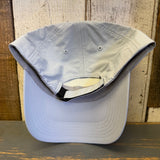 Light grey baseball cap on a wooden surface with a wooden panel background