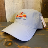 Light blue grey cap with colorful sunset design and Muy Hermosa text on a wooden surface